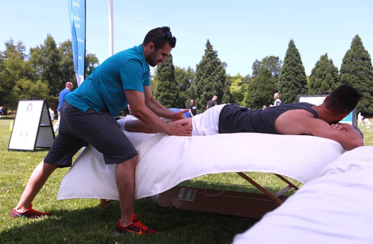Locus Health practitioner providing outdoor massage therapy at community event